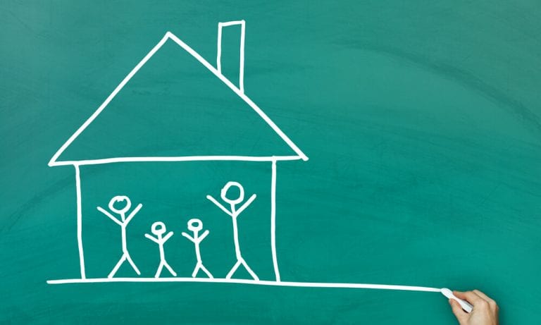 Home with family inside drawn with chalk on chalkboard