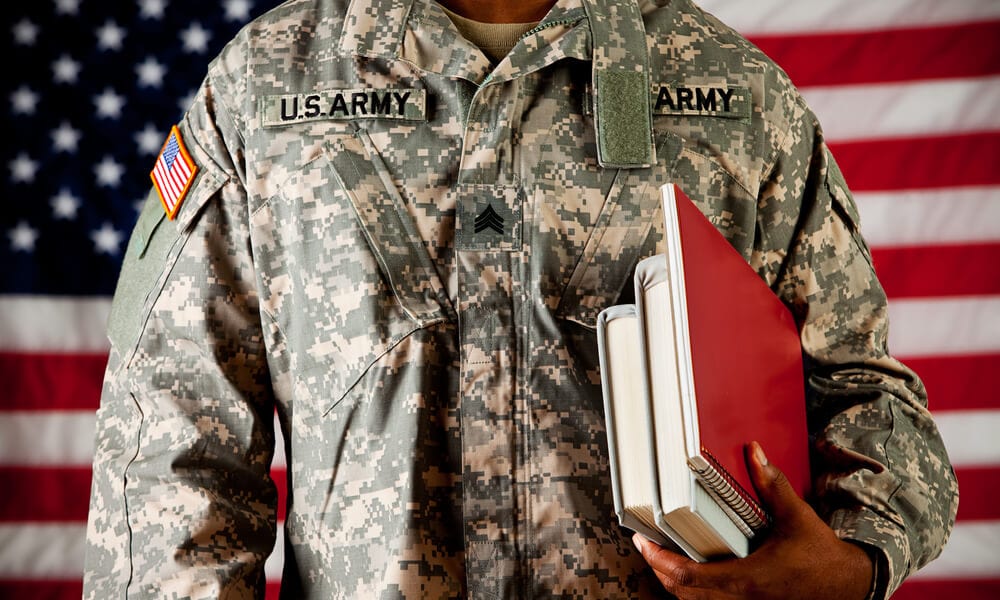 Soldier in uniform holding books in front of American flag