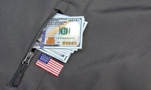 Stack of U.S dollars sticking out of military jacket pocket