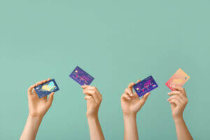 Female hands with multiple credit cards on color background.