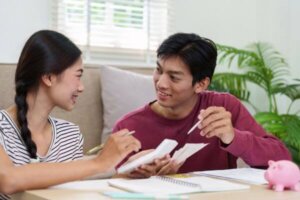 Two young adults engage in budgeting and financial planning while smiling.