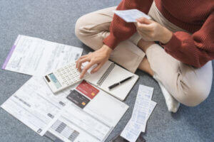 Woman calculating bills and credit cards representing delinquent accounts.