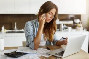Woman on the phone with a credit card in hand representing calling to negotiate.
